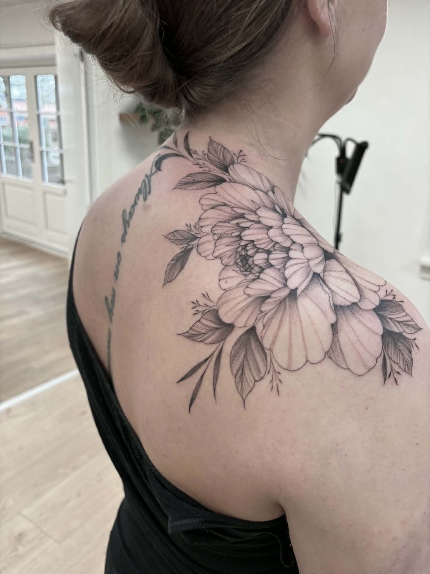 Fine line blomstertatovering på skulder af Nicki