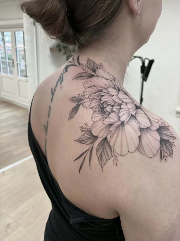 Fine line blomstertatovering på skulder af Nicki